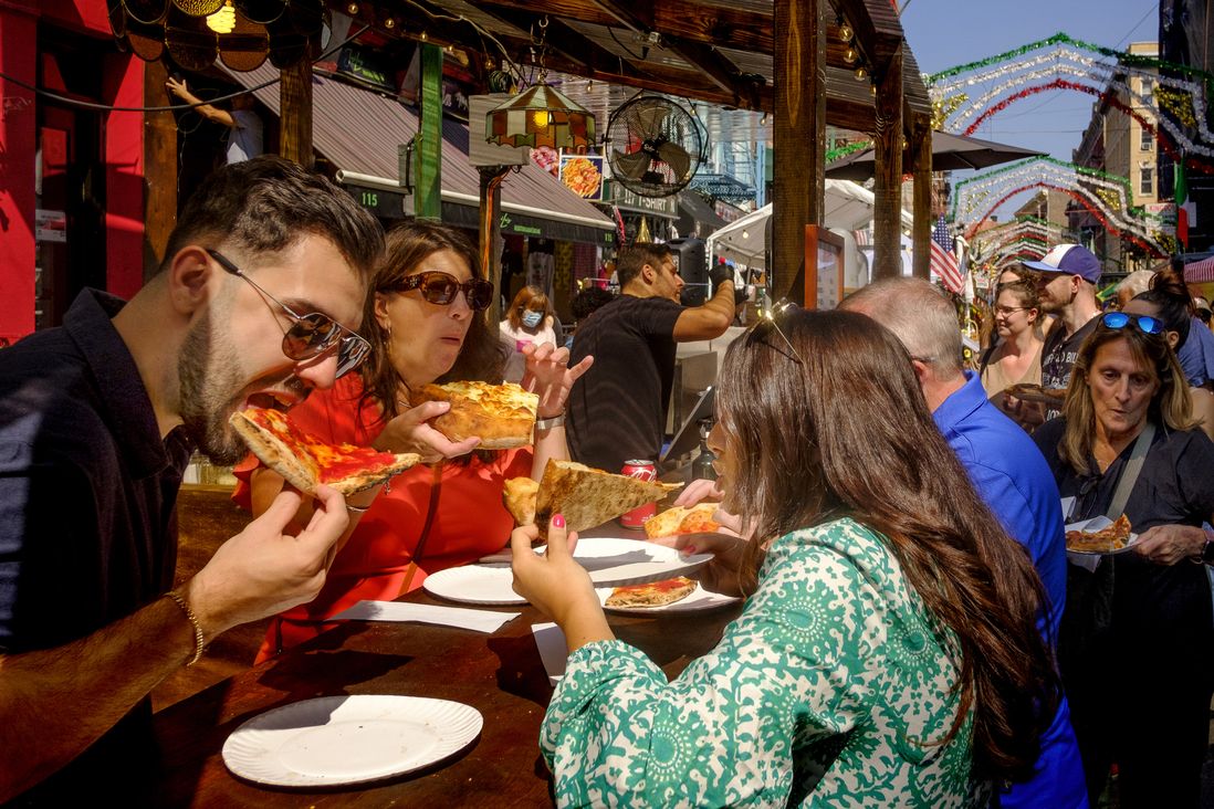 People dine on pizza along Mulberry Street. The Feast of San Gennaro in the Little Italy neighborhood of Manhattan. Saturday 09 17 2022  New York, NY.